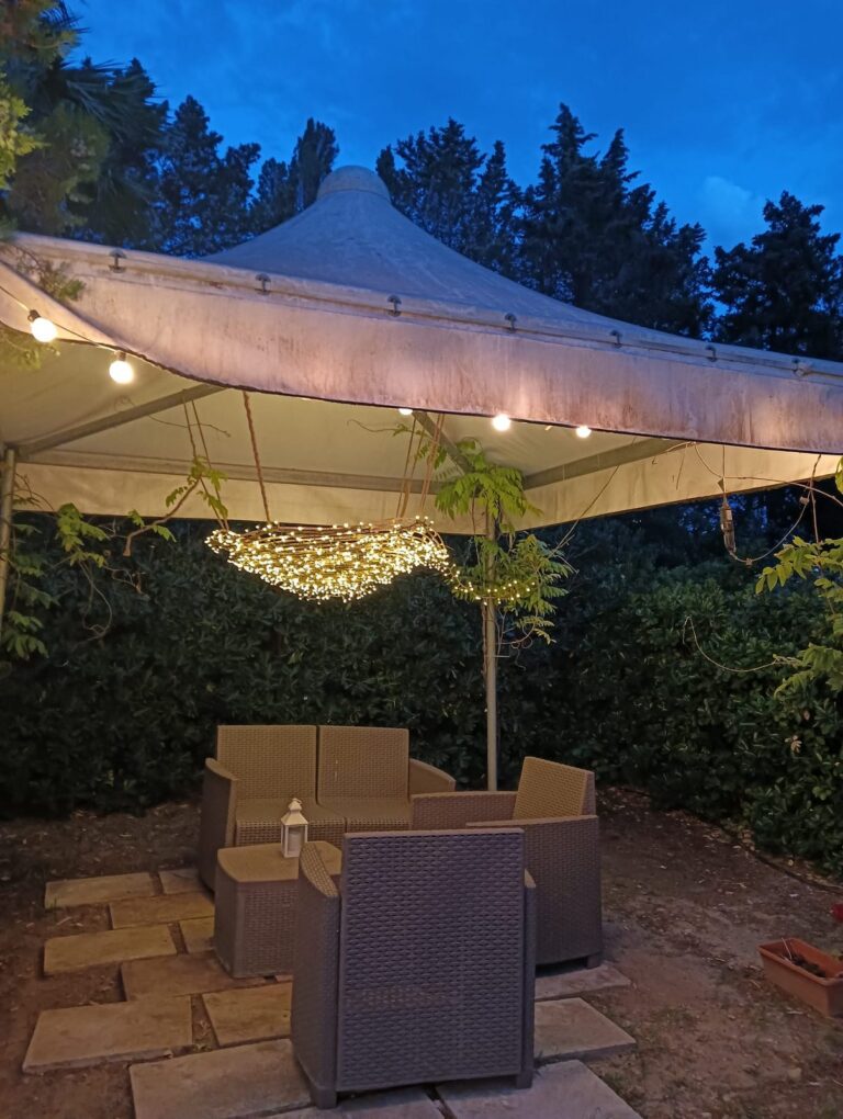Gazebo con salottino e lampadario di luci nel giardino