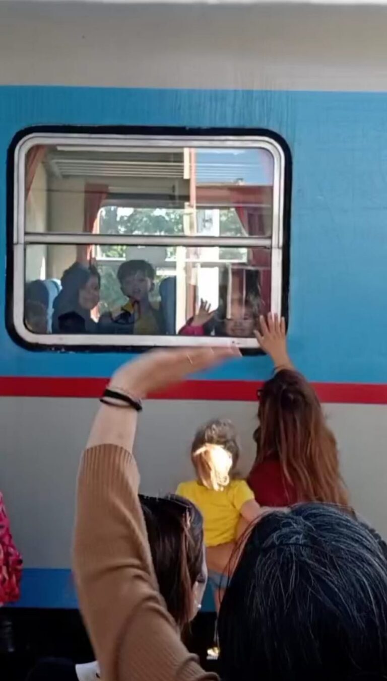 Bambini e adulti salutano dal finestrino di un treno