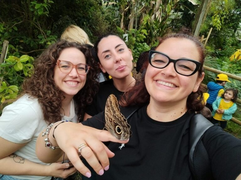 Tre educatrici in una casa delle farfalle, con una farfalla sulla mano